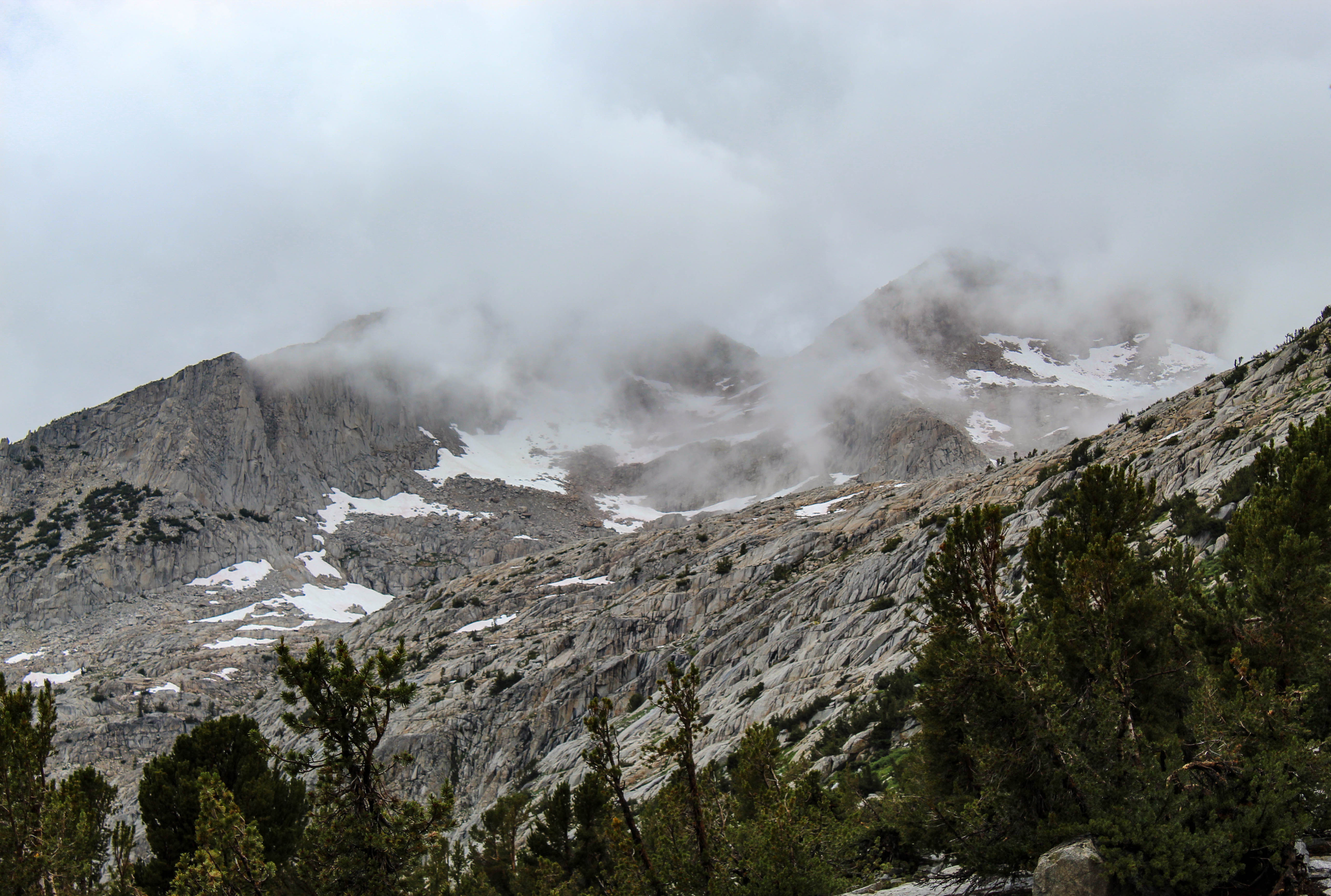 Threatening clouds over a steep mountain pass, viewed from below.