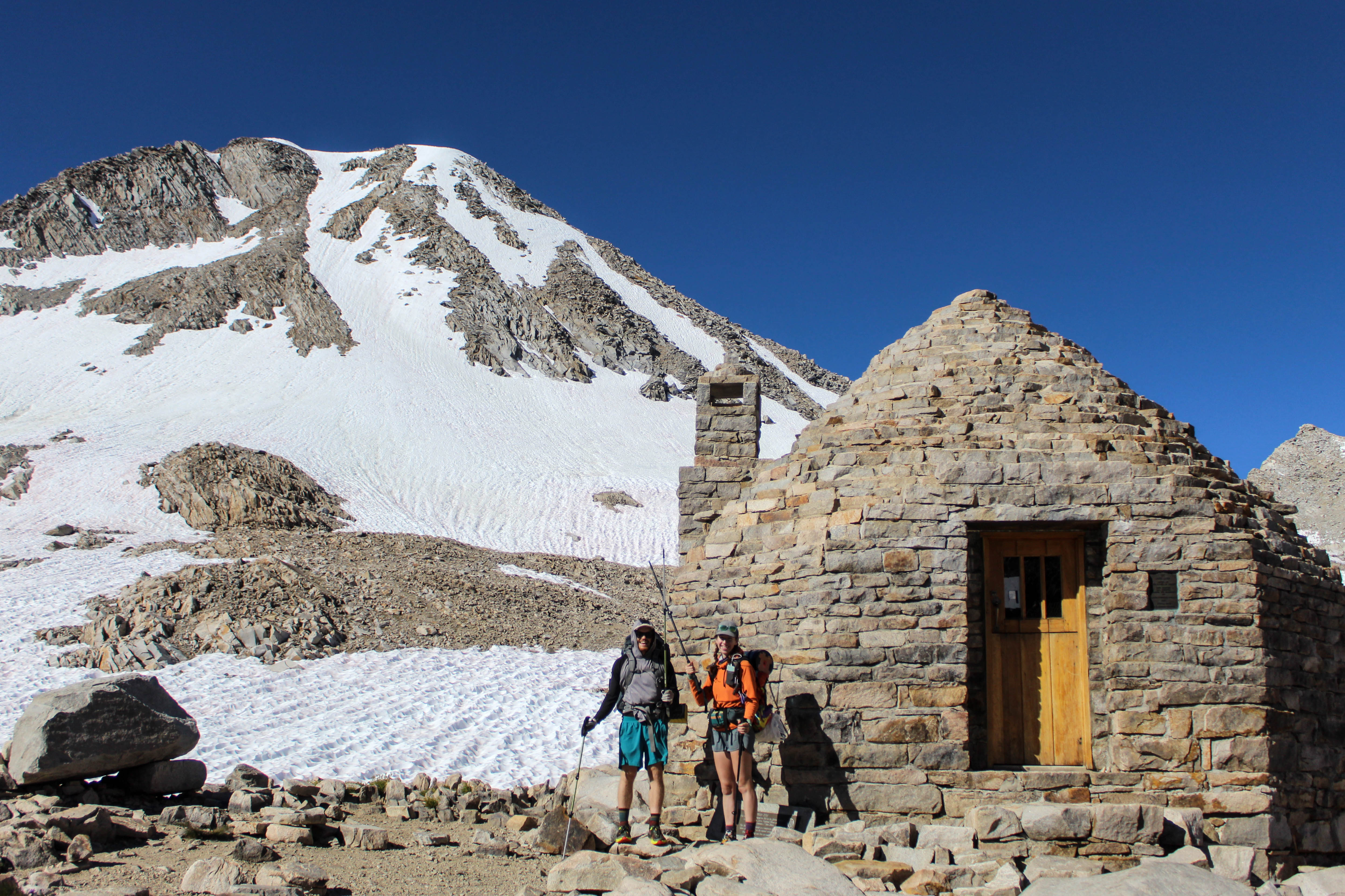 Me and Double Dip standing beside Muir Shelter, a small stone hut with a wooden door, at the top of Muir Pass.