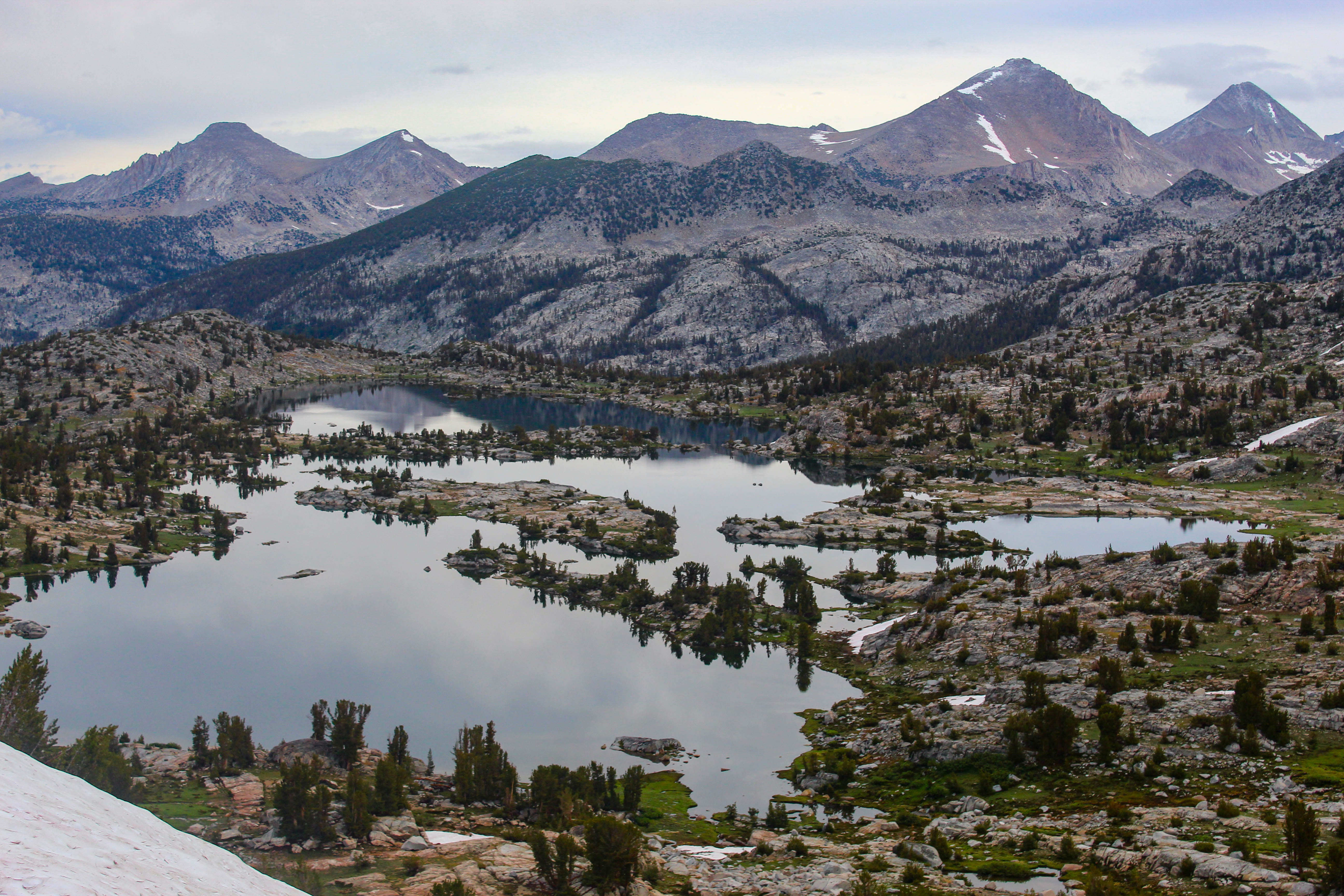 An alpine lake sits amid scattered pines. All sorts of islands and peninsulas poke in to the lake, leaving an irregular shape.