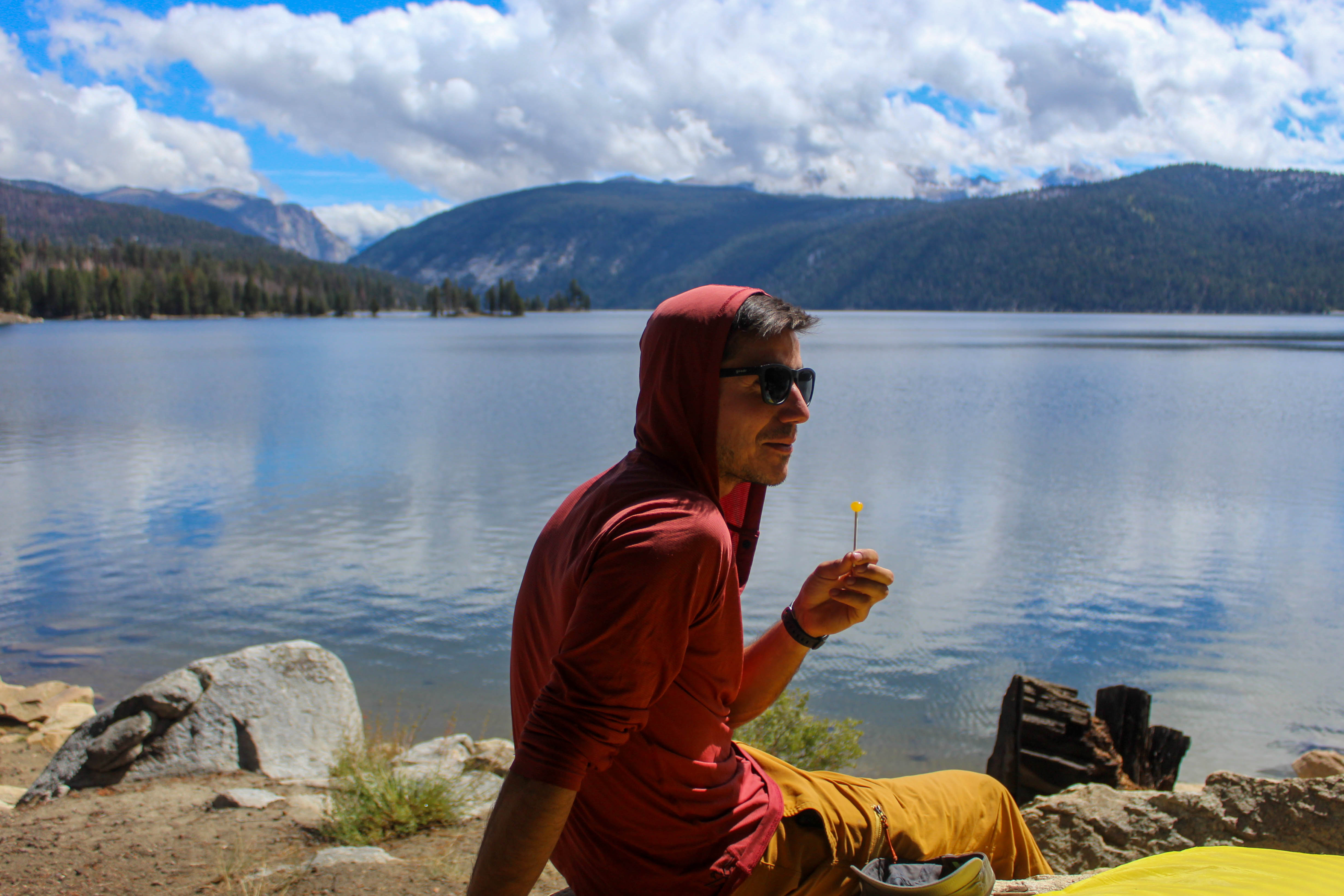 Jib sits at the edge of an alpine lake, licking a lollipop in the sun.