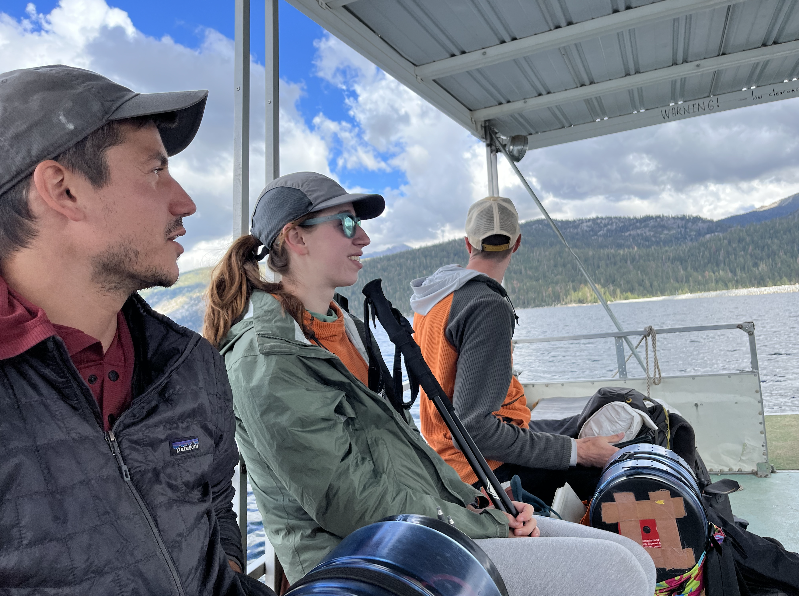 Jib, Double Dip, and Chicken Legs look out over the lake from a small pontoon boat.