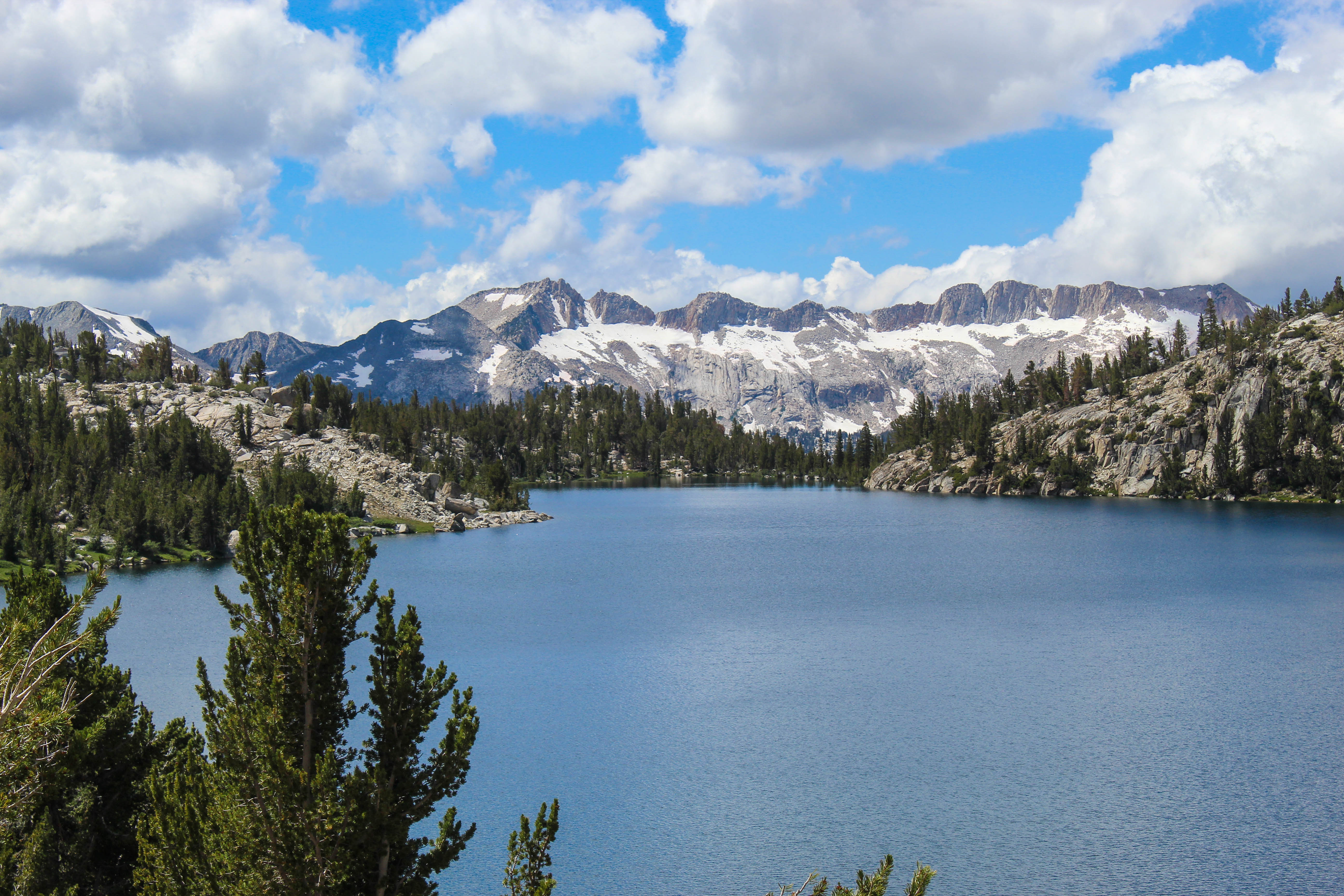 A blue alpine lake gives way to jagged, snow-covered peaks.